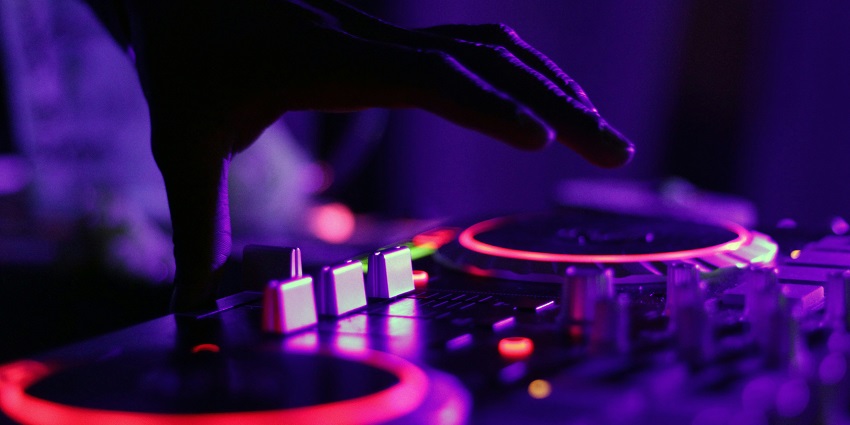 Image of DJ music system and lights on the background in a club people dancing