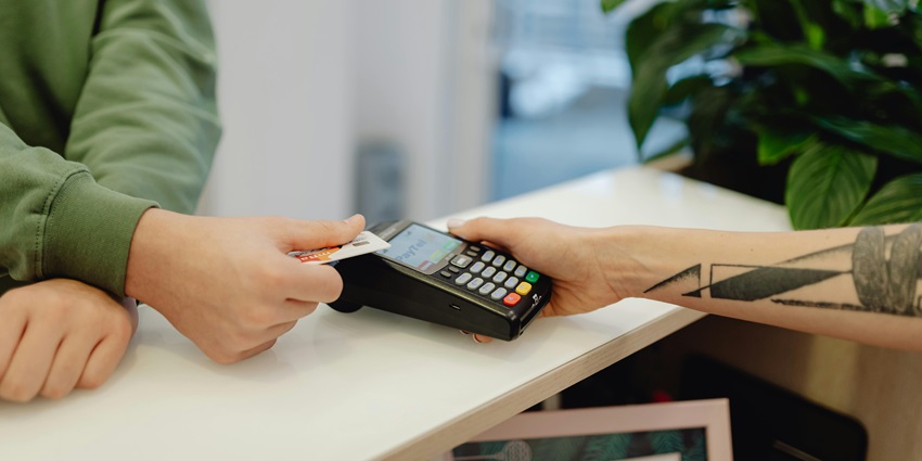A person making a transaction to the cashier through a card with a blurred plant and desk, for paragliding in Maharashtra.