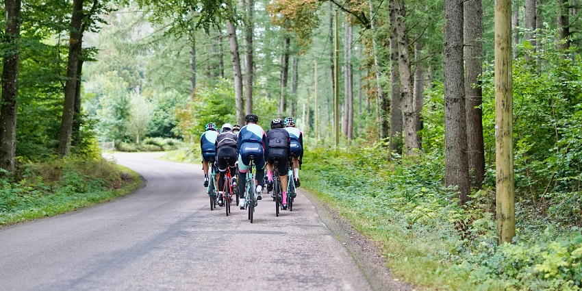 A group of people cycling on a serene path surrounded by lush forests on Gilli Islands.