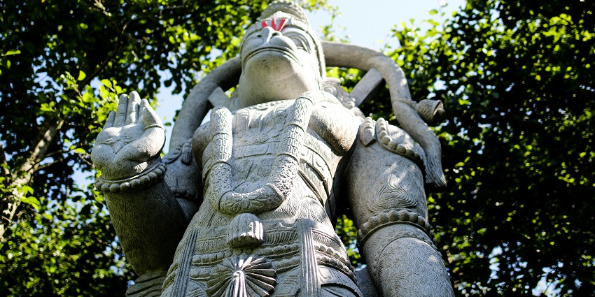 A gray concrete statue of a Hanuman, reminiscent of art at Hanuman temples in Pune.