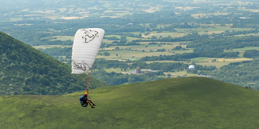 A picture of a person paragliding over a scenic village in Maharashtra covered with lush greenery