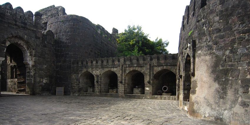 View of Daulatabad Fort stands atop a lush hill in Maharashtra surrounded by thick walls.