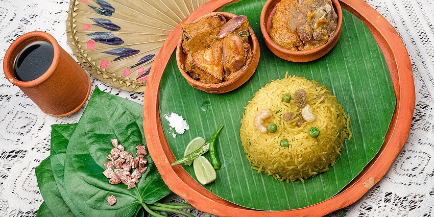 Mutton Masala, served on a banana leaf with veg biryani in traditional Bengali style.