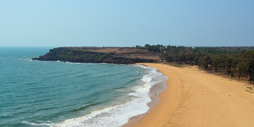 An image of the beautiful Devgad Beach in Maharashtra, with mountains beside it
