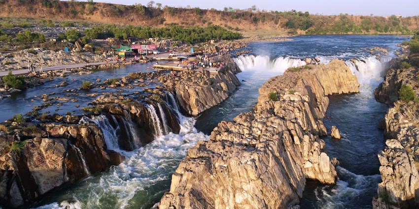 Stunning view of Dhuandhar Falls cascading down the rocks surrounded by lush greenery.
