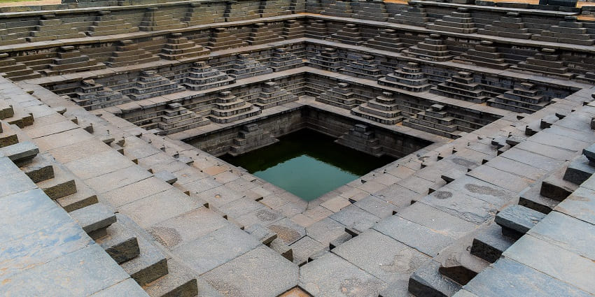 Queen’s Bath, a royal bathing complex in Hampi, with an open-air structure and ornate carvings.