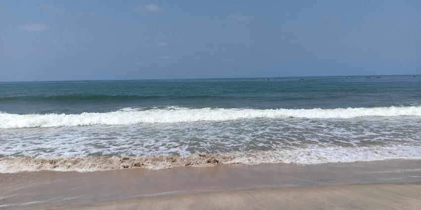 A tranquil view of Tannirbhavi Beach with golden sand and gentle waves.