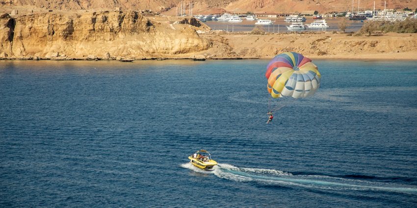 Feel the thrill of adventure with an aerial view of a person parasailing high above