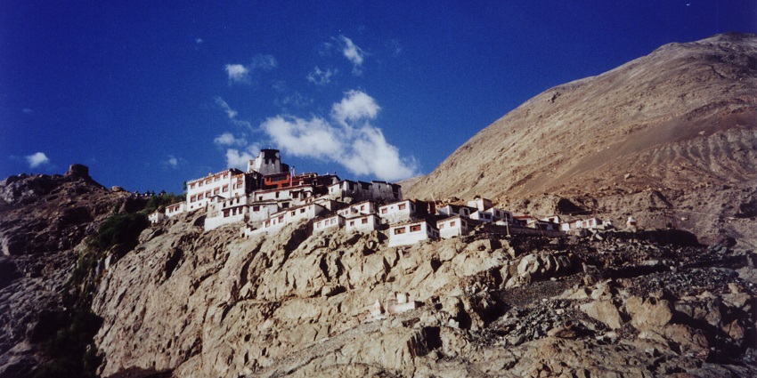 A picture of a monastery taken from down under with a mountain visible
