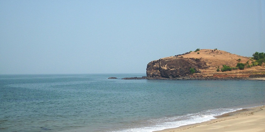 View of Diveagar Beach, featuring golden sands and gentle waves under a clear sky.