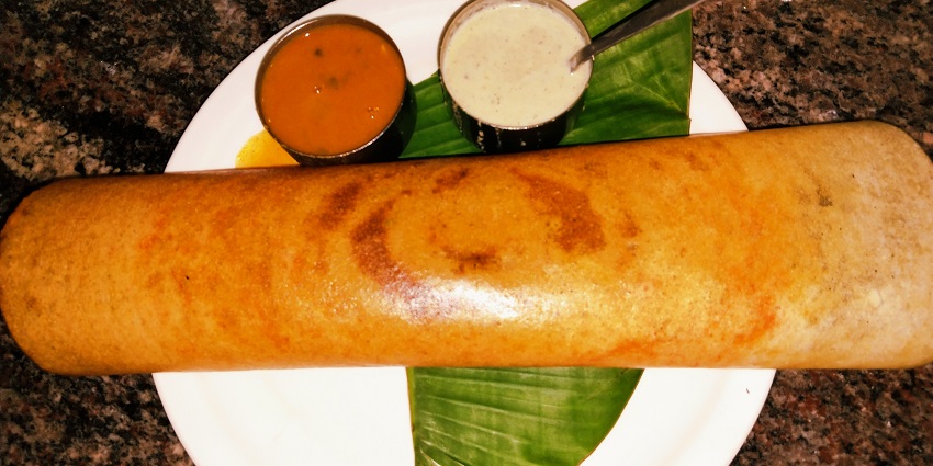 Image of a masala dosa served with coconut chutney and sambhar curry
