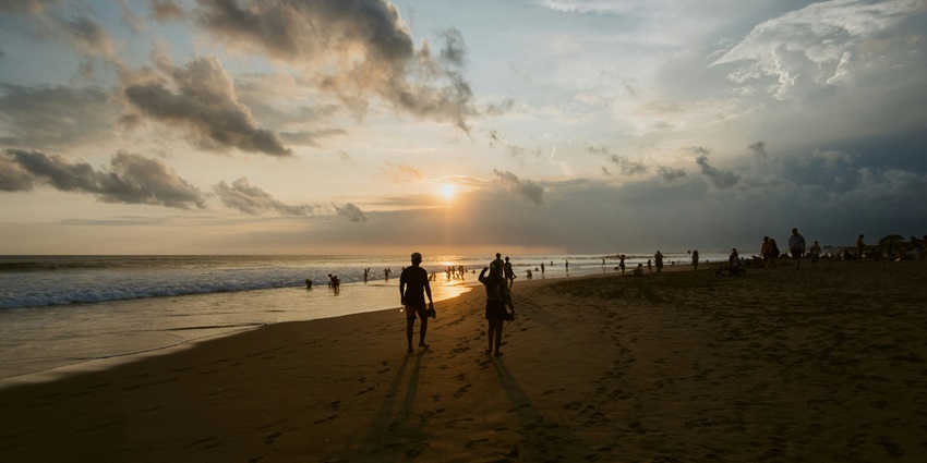 A scenic view of sandy Dreamland beach with sunset glistening on the water.