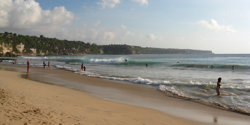 Panoramic view of Dreamland Beach, vast expanses of sand reveal surfers happily playing.