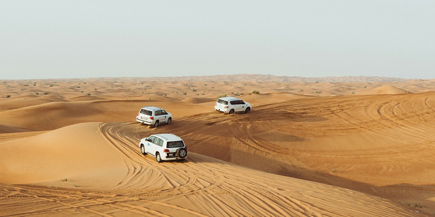 Several cars riding over big dunes in a desert, during an evening safari in Jaisalmer.