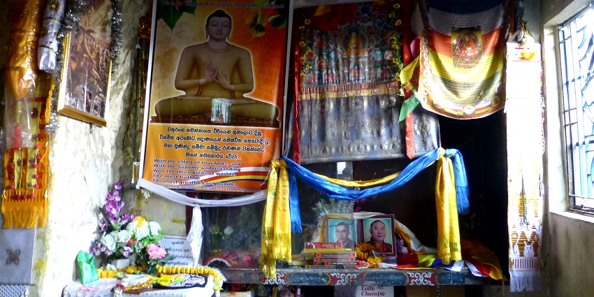 People are offering prayers at the Dungeshwari Cave in the presence of a Buddhist priest.