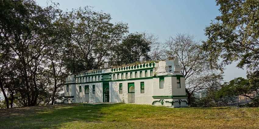 Durgadi Fort in Kalyan with ancient stone walls, arched gateway, and flag atop tower.