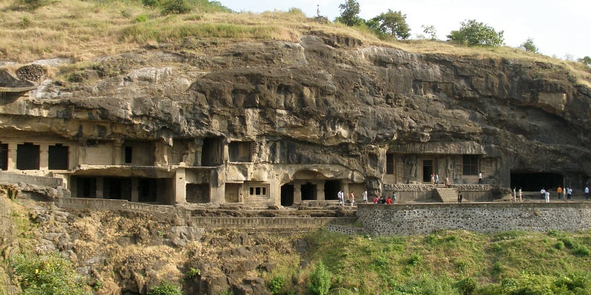 Ancient Buddhist caves with greenery and a mountain popular destination near Pitalkhora Caves.