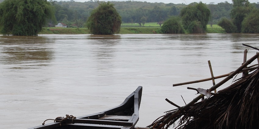 A scenic view of a boat in Kabini River surrounded by greenery under a clear sky.