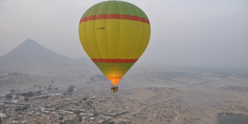 : A hot air balloon filled with people is going up on the sky, leaving the land behind.