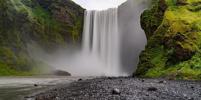A glimpse of water splashing down at high speed and hitting the rocks on the ground.