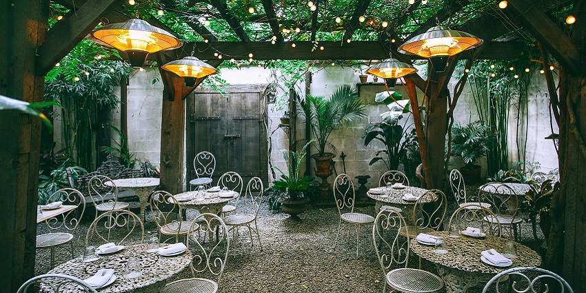 Restaurant in an outdoor like setting and metal furniture surrounded by greenery.