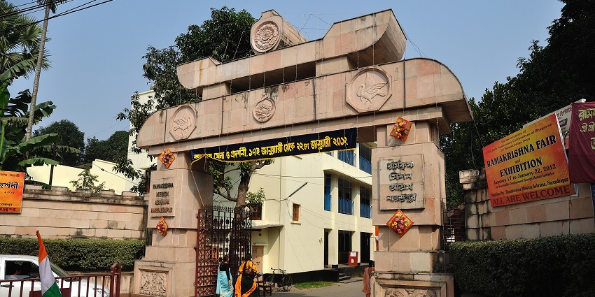 Image of an Ashram entrance gate where people are walking around - similar to the Ramakrishna Mission Ashram in Belagavi