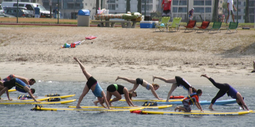 People practicing yoga, one of the best things to do in Canggu on a surfing board.