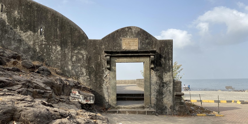 An image showcasing the entrance of the Bandra Fort with a water body in the background.