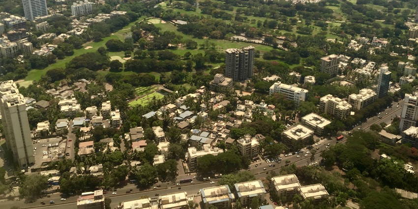 An aerial picture of the Bombay Presidency Golf Club with the lush green field surrounded by tall buildings