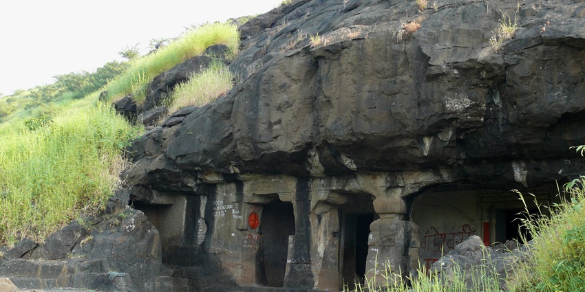A picture of the entrance to a majestic cave system with rocks and forest areas nearby