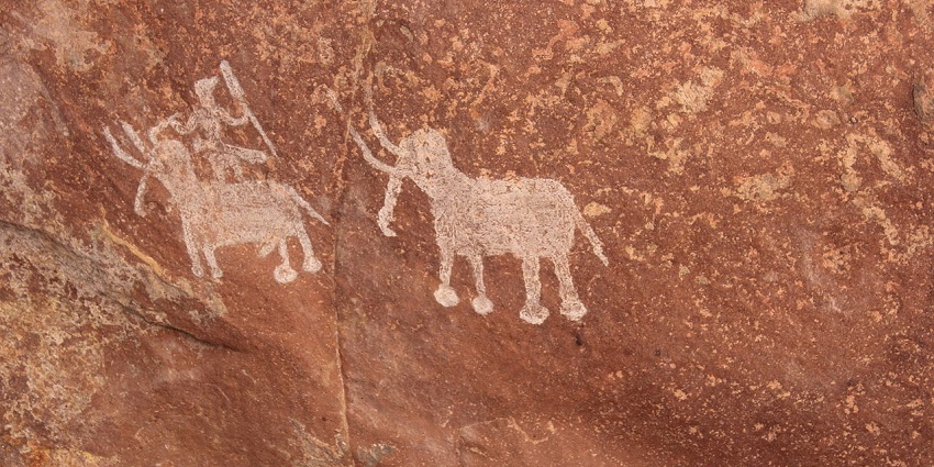 An inner wall of the caves showcasing a painting in which a man is with the elephants.