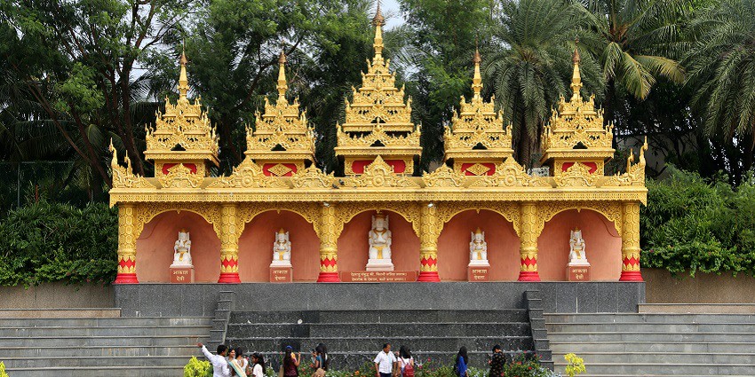 A picture taken in the premises of a Buddha temple with visitors walking in the garden area