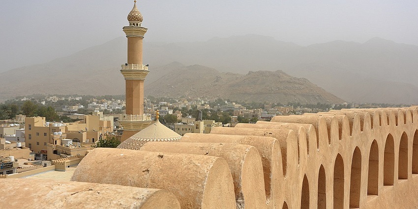 Top of the Nizwa Fort with its imposing towers with the minaret of the Friday Mosque.
