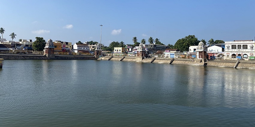 A picture of Mahamaham Tank, with ancient temples and lush greenery, all around.