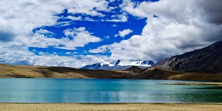 A high-altitude blue lake surrounded by mountains under a clear sky.