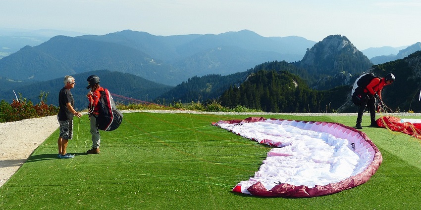 Operator preparing the paraglider before flying and another paraglider standing nearby