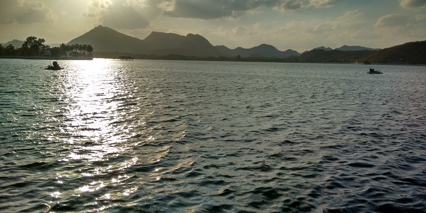 Boats on Fateh Sagar Lake in Udaipur with surrounding hills and islands on the water.