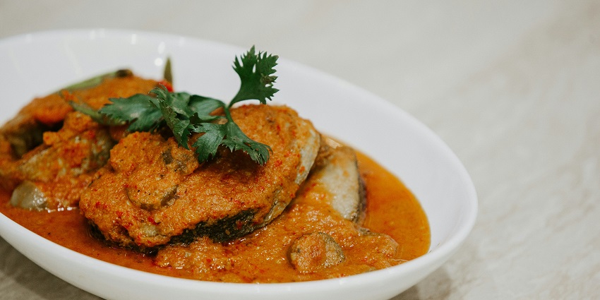Image of fish curry served on a white plate - A platter of various fish dishes, including curry, fry, and pickle
