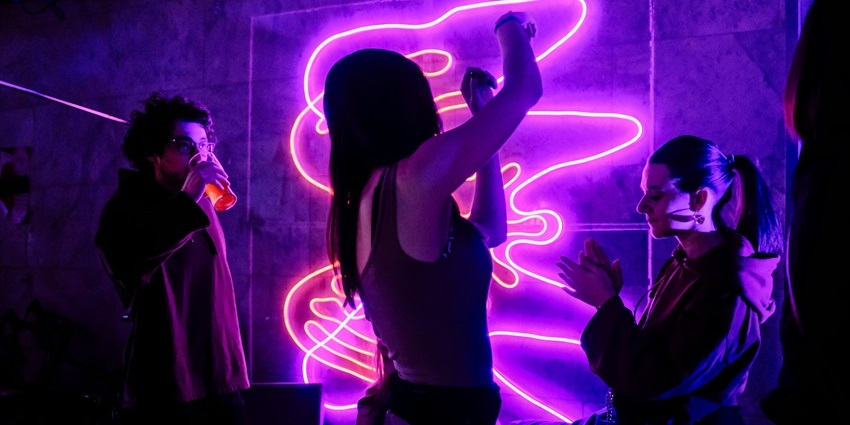 A picture of a woman dancing at one of the party places in Candolim, having neon lights