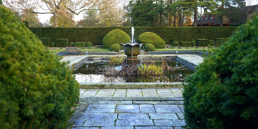 An image showing the Flora fountain surrounded by lush green trees in a serene outdoor setting, creating a peaceful and natural atmosphere.