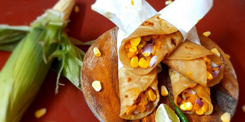 Potato corn frankie rolled on a wooden plate with lemon green chilli and unshaved corn