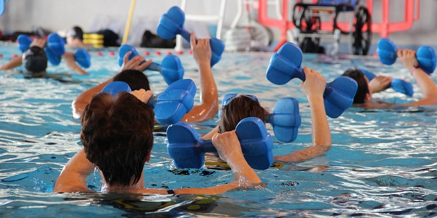 A view of people swimming in a large pool and engaging in some cool water activities.