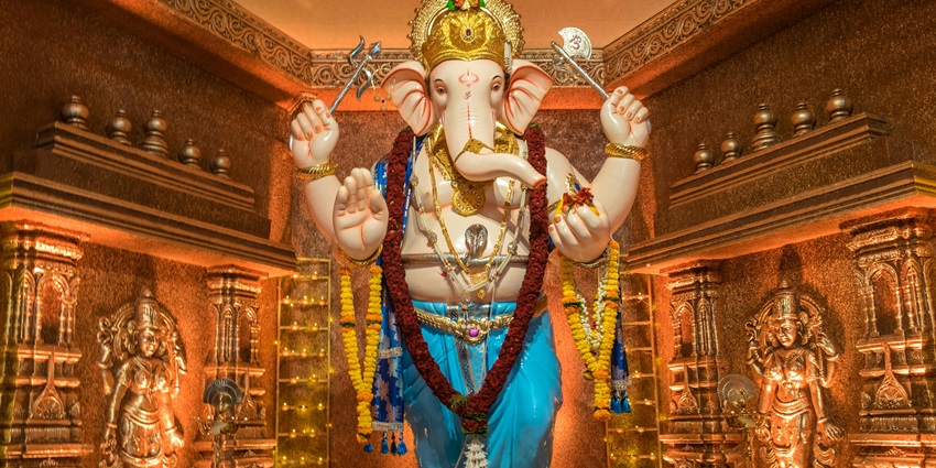 Standing Ganesh statue adorned with vibrant garlands at a festive temple—ganesh temples in mumbai