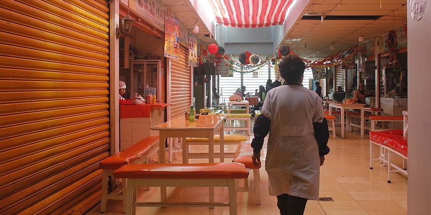 Man walking in the colourful market stalls at Mercado Camacho with little dining space
