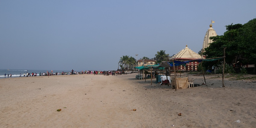 Scenic view of Ganpatipule Beach during the monsoon season, surrounded by lush hills.