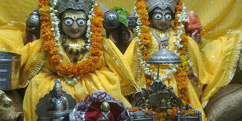 An inner view of a temple showcasing Lord Shiva and Goddess Gauri in yellow clothes.