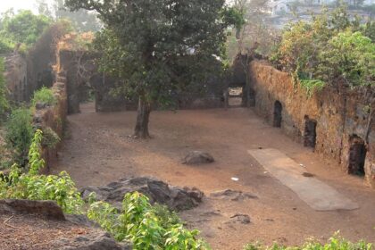 Courtyard of Ghodbunder Fort, showcasing stone walls and greenery.