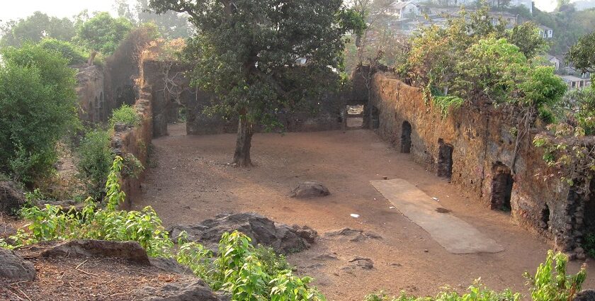 Courtyard of Ghodbunder Fort, showcasing stone walls and greenery.