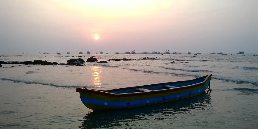 Colourful boat resting on Gorai Beach, framed by golden sands and blue skies.