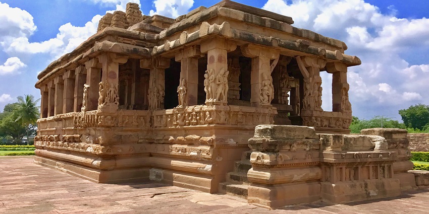 An exterior view of an ancient stone temple with intricate carvings on its outer side
